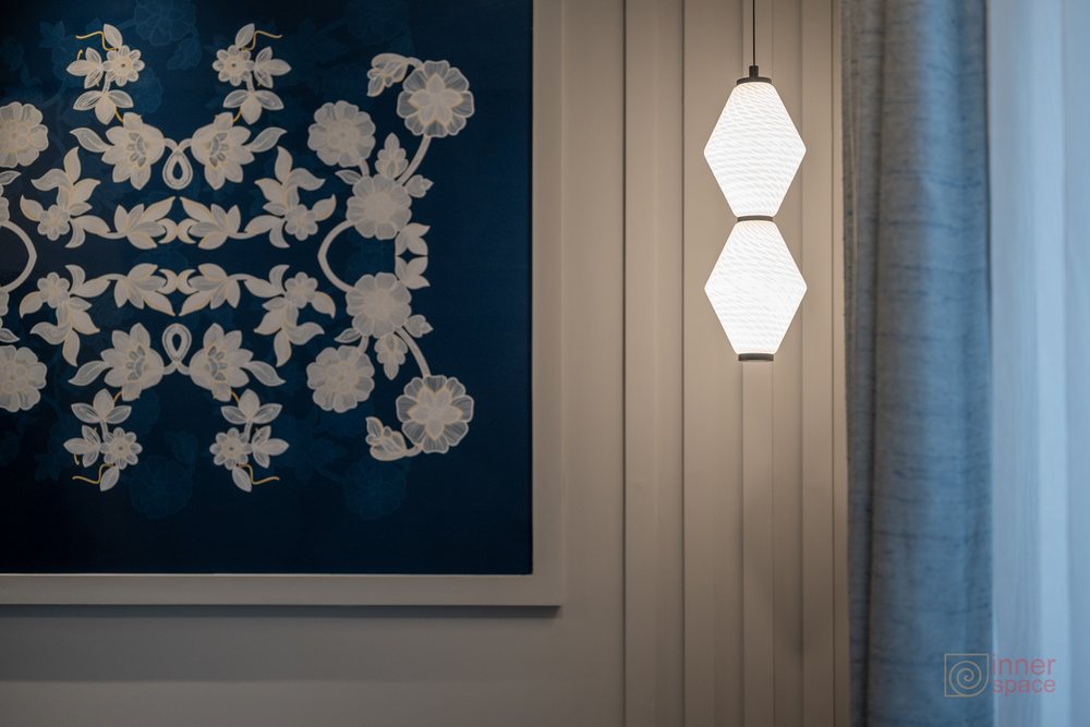 Pendant lights hanging beside a blue floral wallpaper panel and fluted wall panelling