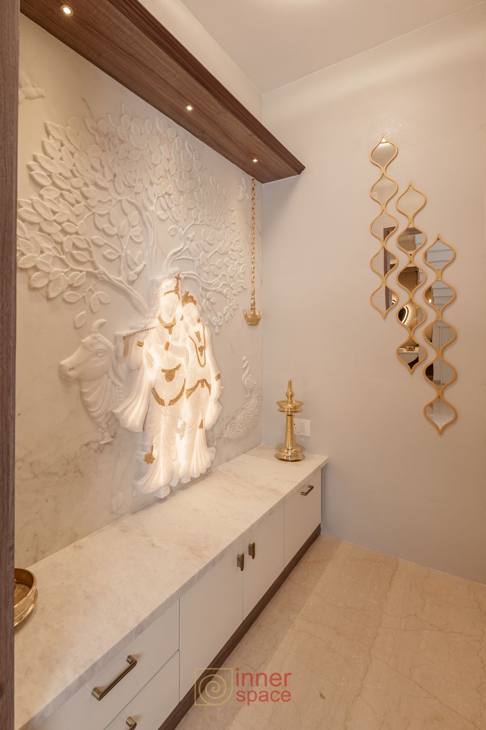 Pooja room with a backlit marble relief and full-depth storage drawers beneath the ledge